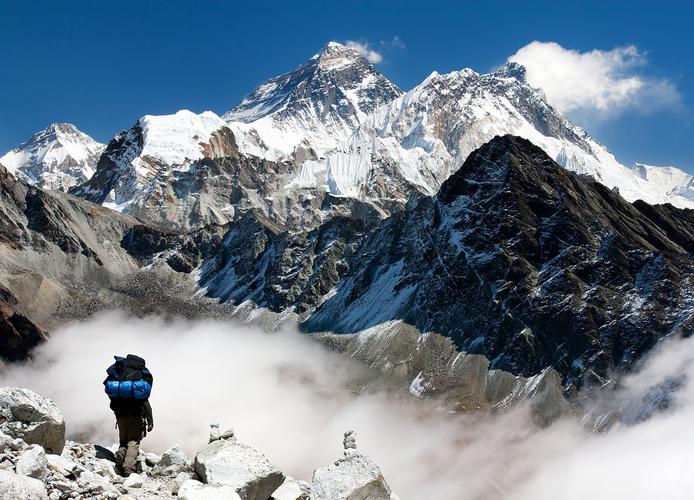 一个登山者站在雪山前的背影
